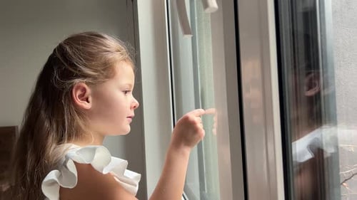 Little Girl Looking Out the Window in Rainy Day