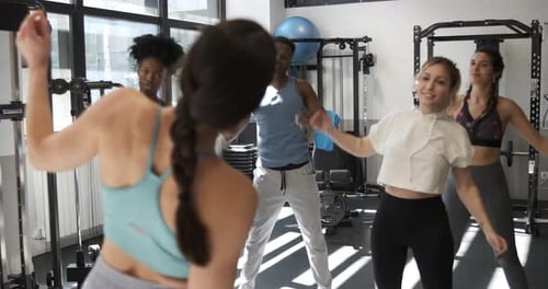 Sportspeople Doing Side Bends with Trainer at Gym