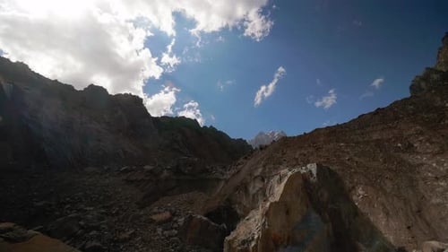 Time-lapse of floating clouds against blue sky over mountains or mountain.