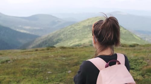 Young Brunette Woman Standing on a Peak of Rock and Looking at the Mountains Landscape