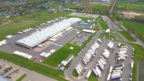Aerial shot of industrial warehouse. Loading hub and many trucks with cargo trailers. Aerial view of