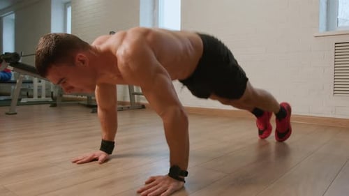 Young Man in Black Shorts Workout in Gym and Does Pushups and Jumping While Standing in Plank