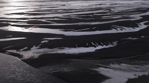 Dramatic aerial drone shot of a river winding through volcanic terrain in Iceland, with