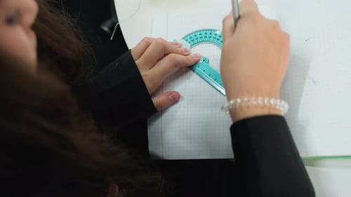 Young Student Using a Protractor and Pencil in a Gridded Notebook