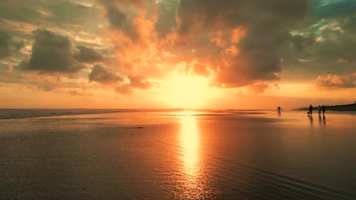 A Stunning Aerial View of a Bali Beach at Sunset with People Walking Along the Shore