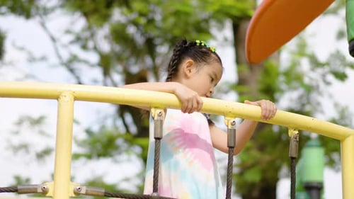 Adorable asian girl play on the playground in the park, hanging on their hands like monkeys