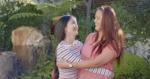 Loving Mother and Teen Daughter Embrace in Garden
