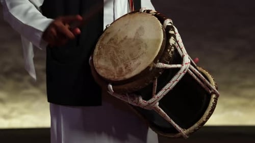 Hombre tocando la batería tradicional emiratí, instrumento de percusión solo con las manos en el marco