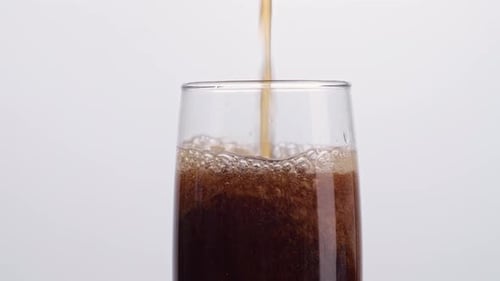 Close Up Of Fresh Cola Being Poured In To The Glass On White Background