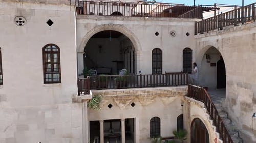 Woman Standing on Balcony in Courtyard