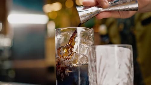 professional bartender creates a cocktail drink pours alcohol into a measuring glass at the bar
