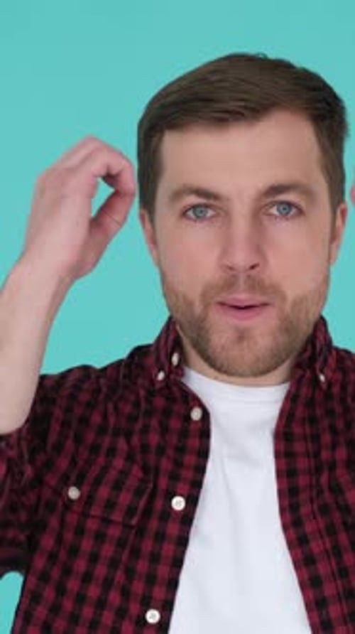 Caucasian Young Man with a Tired Face in the Studio on a Blue Background Vertical Video
