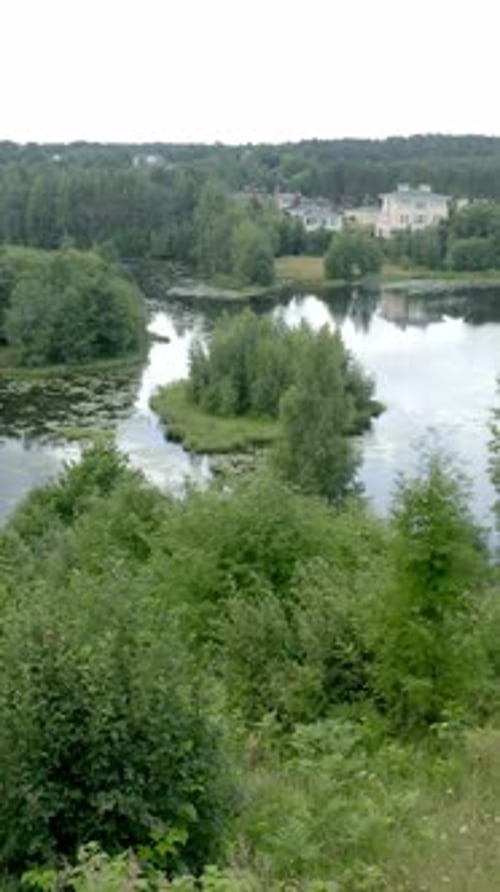 Vertical of Man Practices Yoga Wheel Pose on Mat on High River Bank