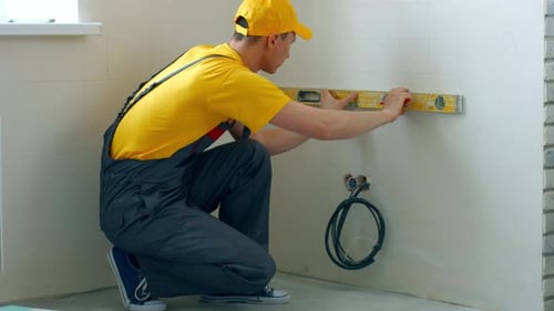 Der Baumeister macht mit einem Nivellierwerkzeug Markierungen an der Wand