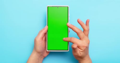 Woman's Hands Holding Smartphone with Green Screen on Blue Background