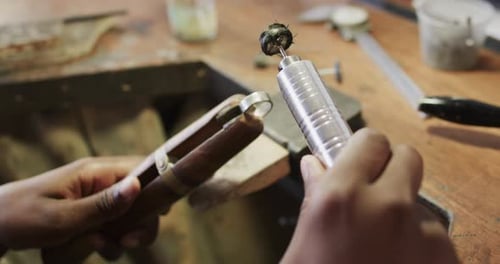Biracial female worker shaping ring using handcraft tools in workshop in slow motion