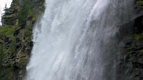 Slow Motion Of Water Falling Down From Big Waterfall in Alps Nature Background