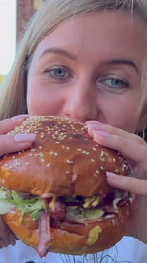 A Young Woman Eats a Meat Burger in a Fast Food Restaurant Portrait of the Face of a Woman Who is