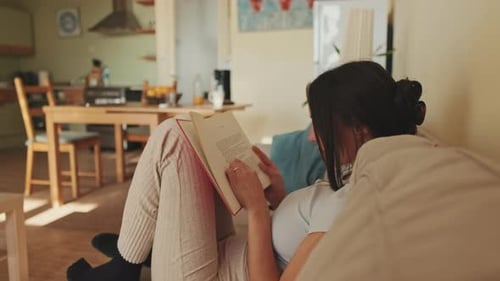 Woman Reading Book Relaxing on Couch Indoors