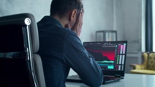 Operador de criptomonedas en su lugar de trabajo frente al monitor de una computadora portátil con corrección bursátil