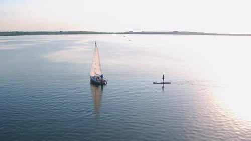 Birdseye Shot of Cinematic Peaceful River Scenery Sailing White Yacht and Supsurfing Tourists