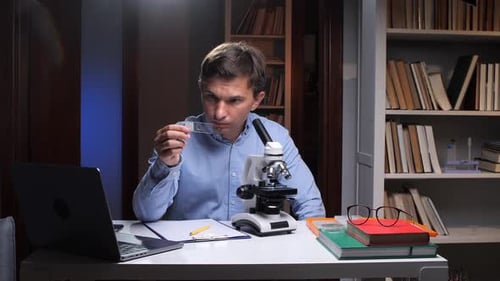 Scientist Analyzing Sample with Microscope in Laboratory at Night