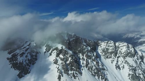 Alpenlandschaft mit schneebedeckten und wolkenbedeckten Gipfeln