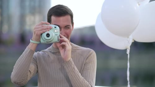 Smiling Person Taking Photos with Instant Camera Balloons