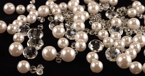Transparent white jewelry crystals, rhinestones and pearls on black velvet.