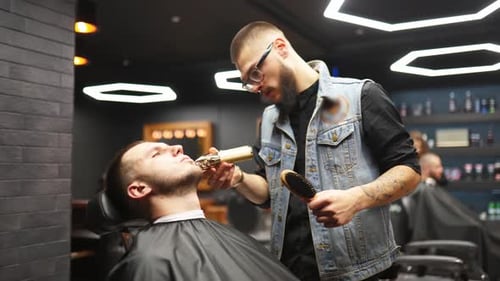 Barber Trims Young Man's Beard in Stylish Barbershop