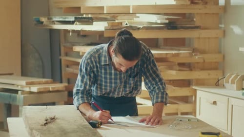 Carpenter Using a Tape Measure Ruler to Measuring Wood Board in a Loft Studio