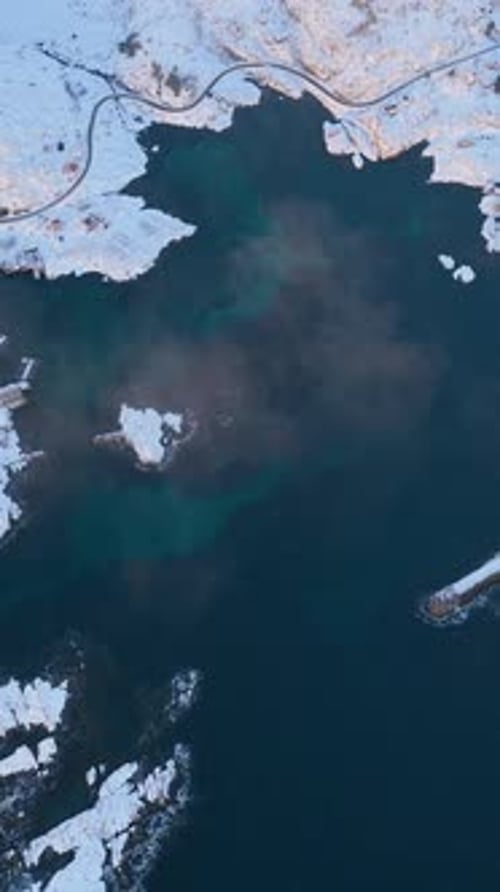 Aerial Top Down View Of Snowy Lofoten Coastline And Blue Ocean