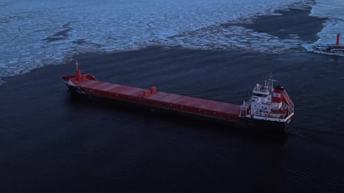 An Airborne Perspective Captures Freighter Navigating Icy Strait with Tug Support and Lighthouse