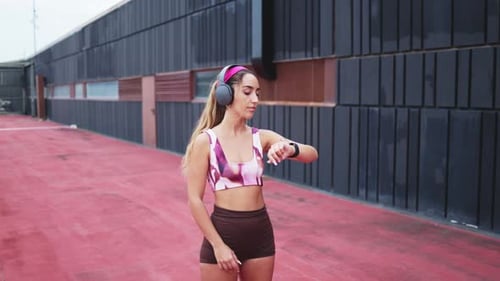 Woman Checks Smartwatch with Headphones Outside