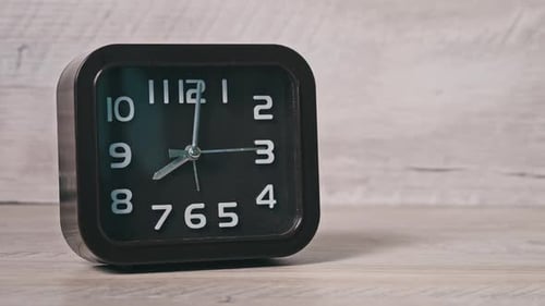 El reloj puntero de forma cuadrada sobre mesa de madera muestra la hora 8 horas