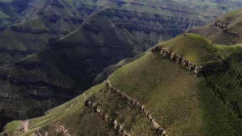 Verdant Mountain Peaks and Valleys Under a Cloudy Sky with Roads Curving Around the Slopes