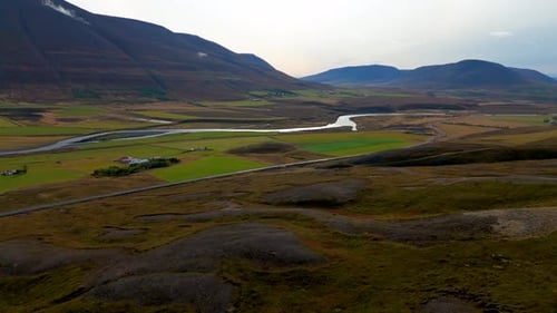 Aerial revealing shot of a river running through a mountain valley in Iceland