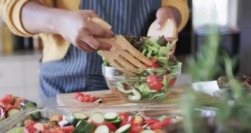 Woman Mixing Salad in Bowl at Home