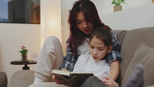 Woman and Child Reading a Book on Couch