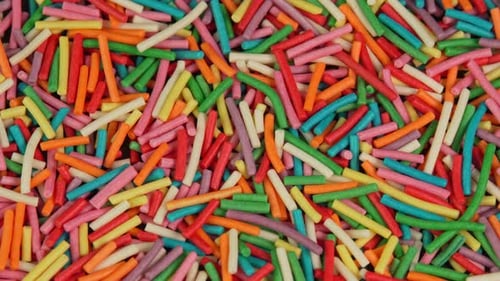Colored confectionery sprinkles rotate in macro. Culinary topping for desserts and baked goods