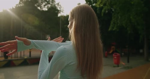 Sporty Girl in Blue Activewear Warming Up Before Workout in Park