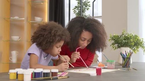 Cheerful African American Mother and Little Daughter Straw Painting Together