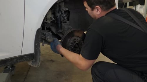 A Mechanic Repairing Car Shock Absorbers in a Car Service Station