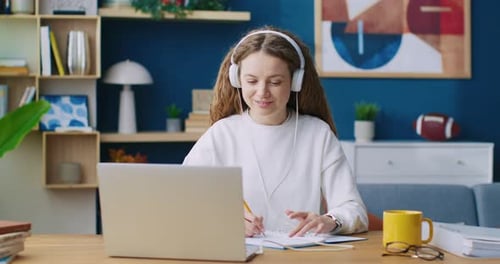 Young Woman Using Laptop and Writing at Home
