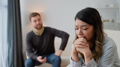 Sad Woman Grieving with Man in Background