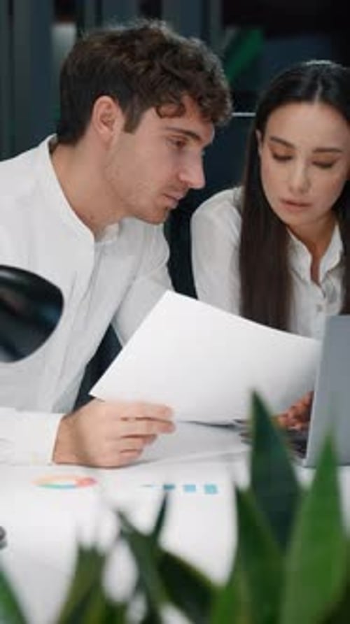 Two Business Partners Talking Looking in Papers with Stats Data Graphs of Project Marketing Result