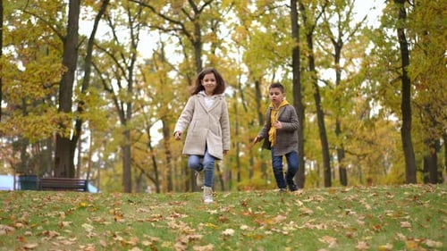 Laughing Caucasian Brother and Sister Running in Slow Motion Downhill Leaving Wide Shot Front View