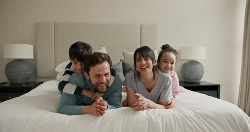 Happy Family Posing on Bed Together Indoors