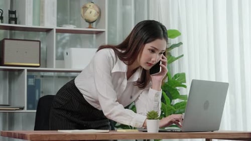 Woman Using Laptop and Smartphone in Office