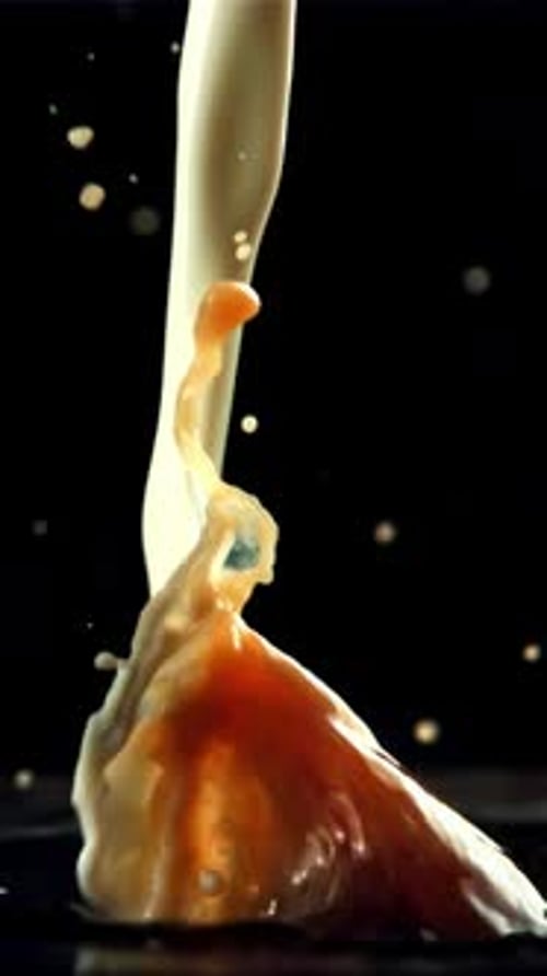 Stream of Milk with Splashes Falls Into Black Coffee Filmed is Slow Motion 1000 Fps
